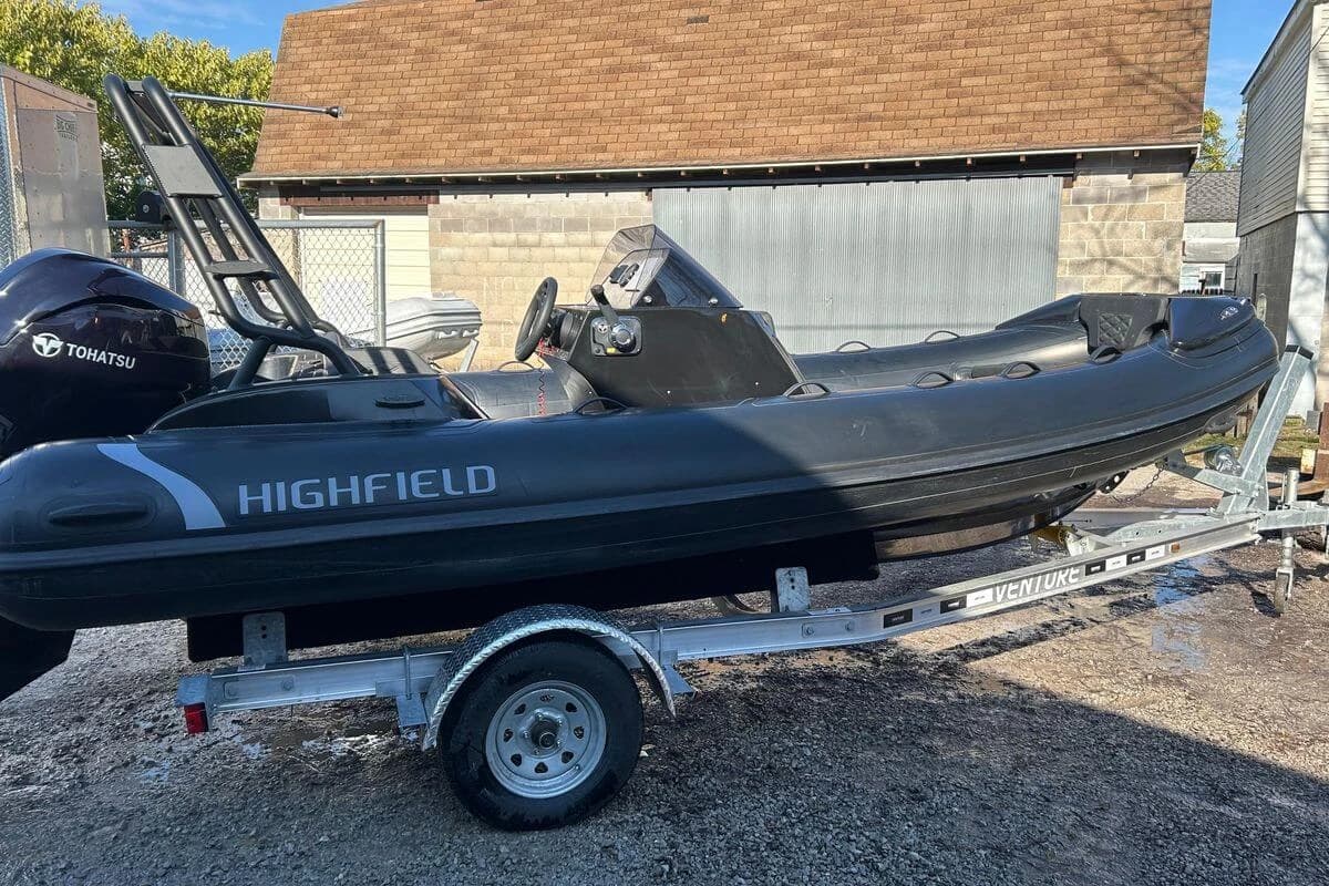 2025 Highfield Sport 520 boat on trailer, featuring Tohatsu engine, parked outdoors.